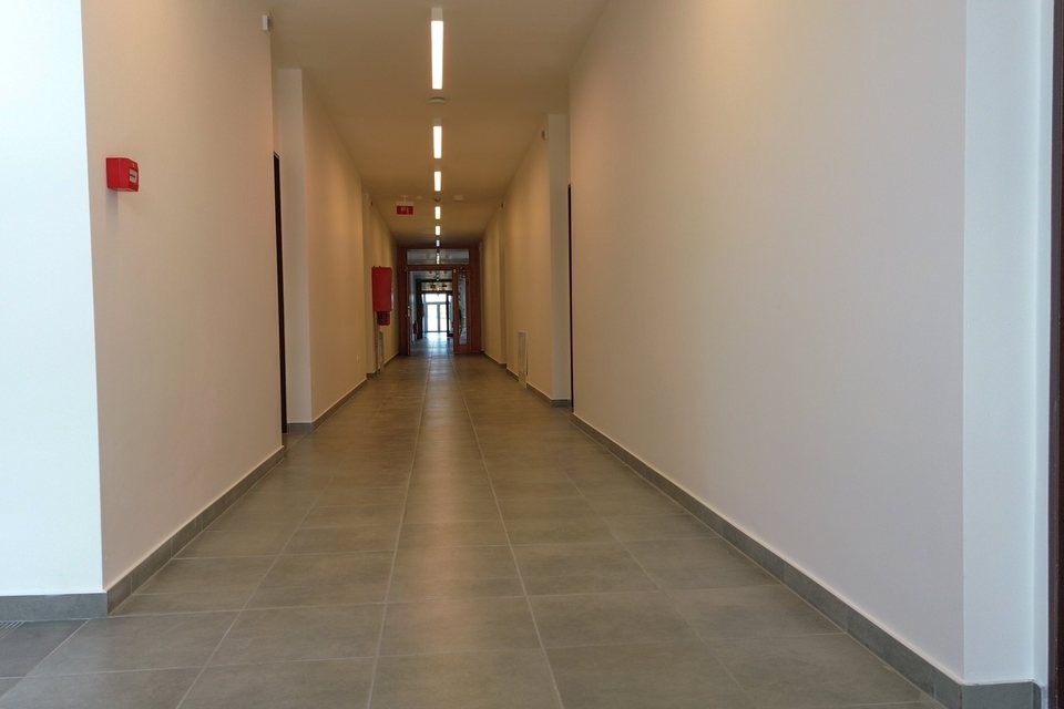 Široká chodba s madlom pozdĺž steny a dverami do izieb