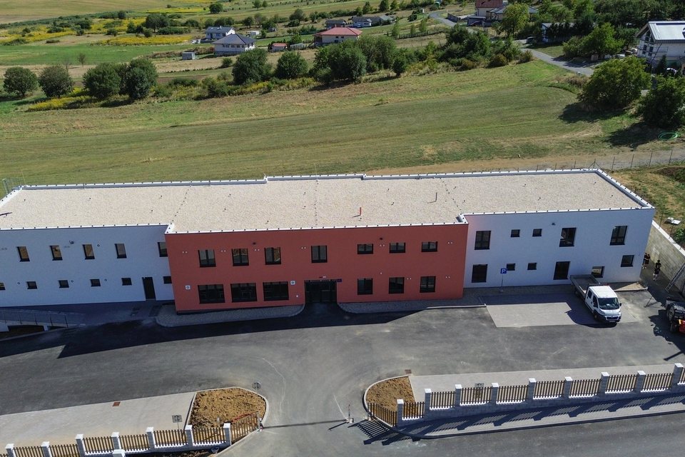 Pohľad zhora na dvojpodlažnú budovu zariadenia s parkoviskom pred vstupom